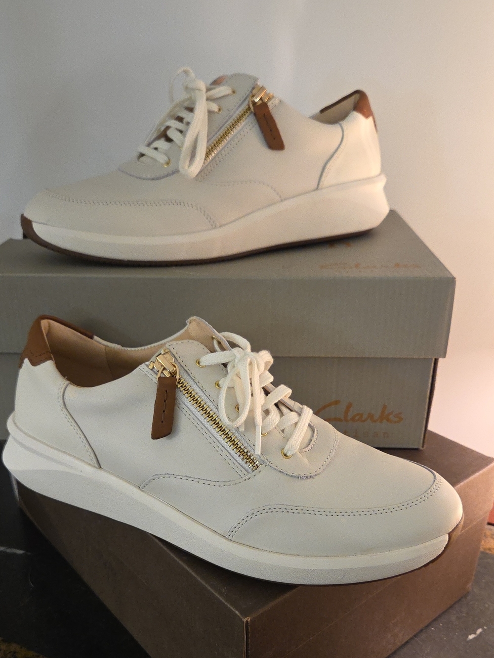 Clarks Cream Leather Sneakers with Brown Heel Accent and Gold Zip